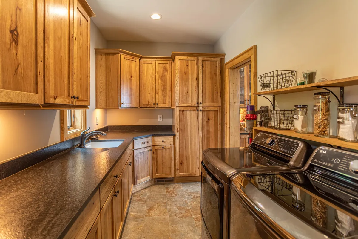 This image focuses on wooden cabinetry, a black countertop, and stainless steel appliances. The scene is warm and functional, illustrating a well-stocked, practical kitchen environment that’s equally suited for casual breakfasts or elaborate dinners.