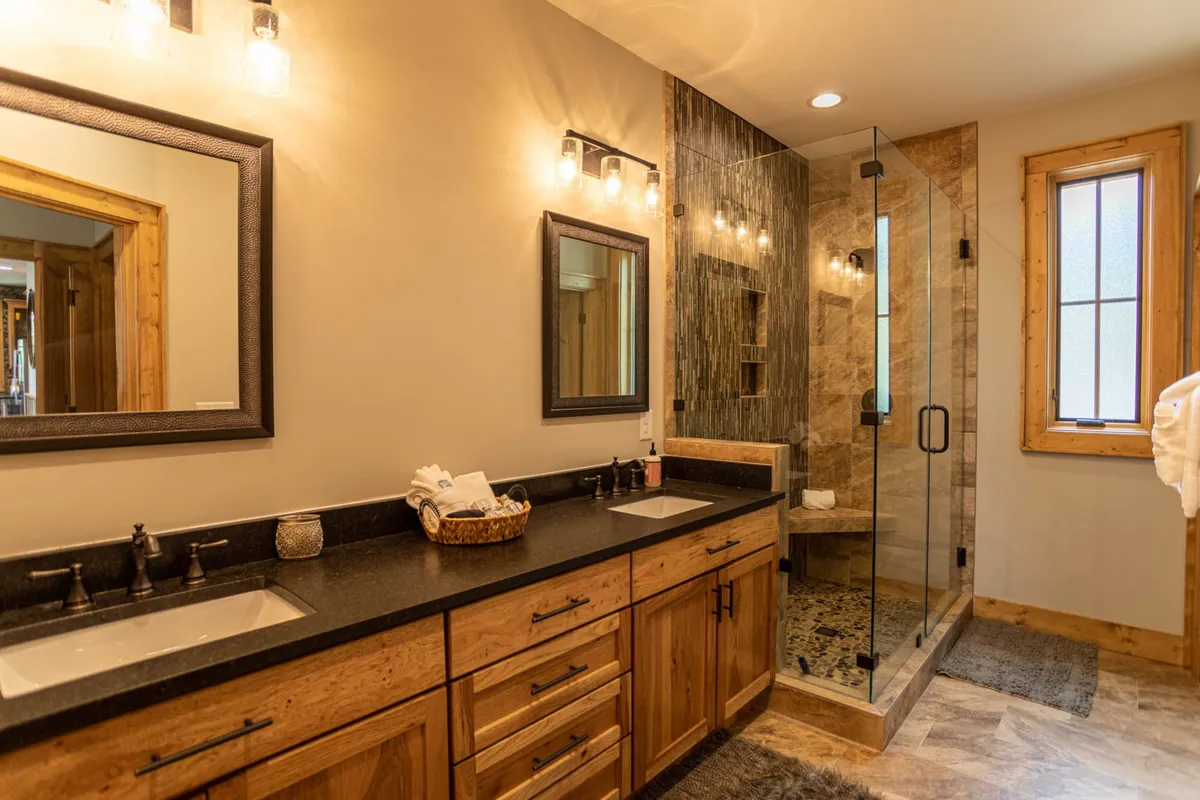 A spa-inspired bathroom with a double sink vanity, modern shower enclosure, mirrored cabinets, and natural wood accents, evoking a sense of luxury and relaxation.