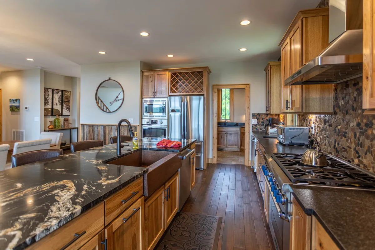 Featuring a large kitchen island, stainless steel appliances, wood cabinetry, and a granite countertop, this kitchen space highlights areas ideal for meal prep and group gatherings. The layout supports both cooking and socializing, echoing the section’s focus on convenience and culinary creativity.